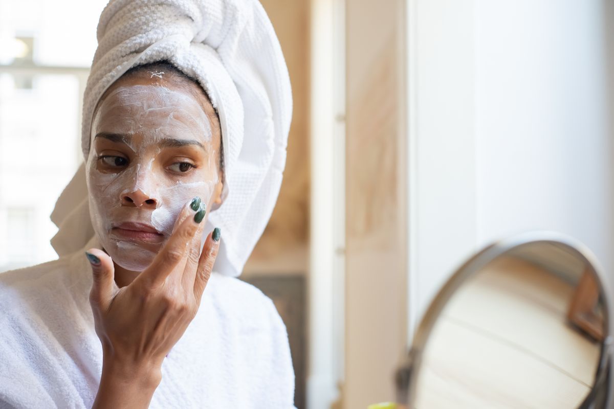 A woman applies face cream during her morning routine