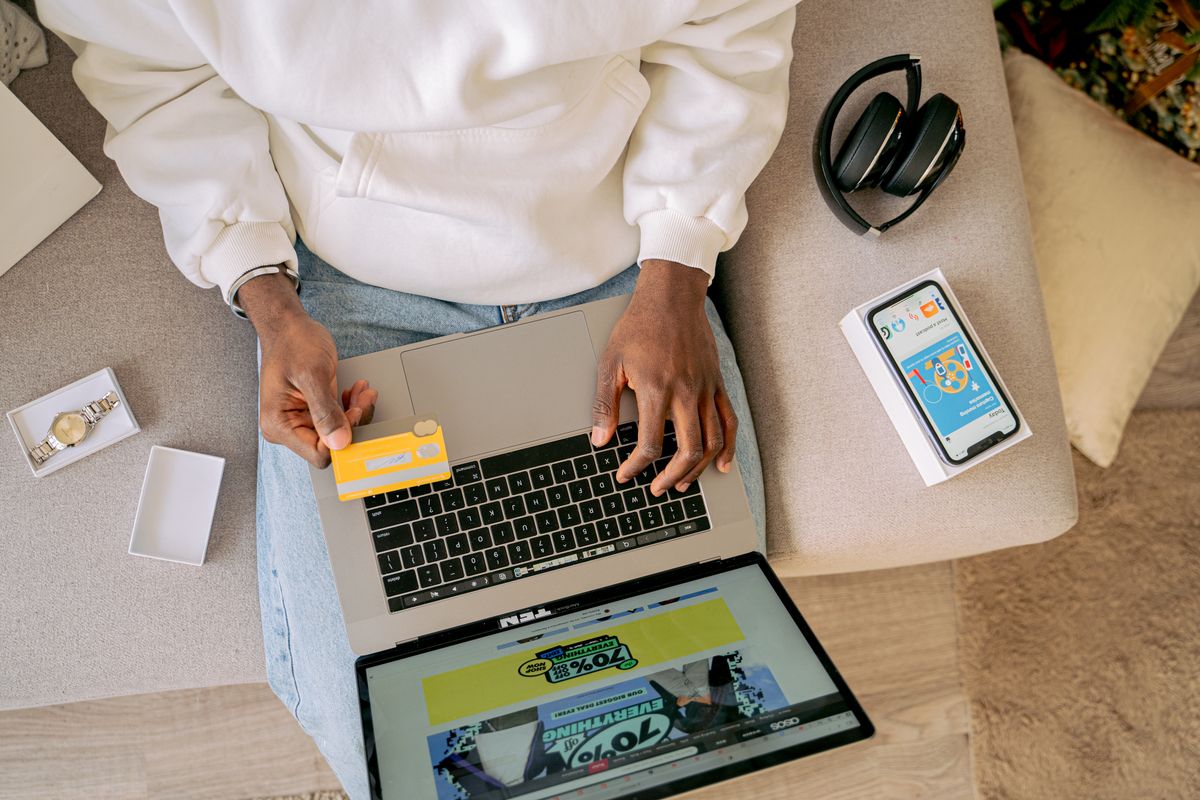 Shopping online with a credit card, headphones and phone at hand