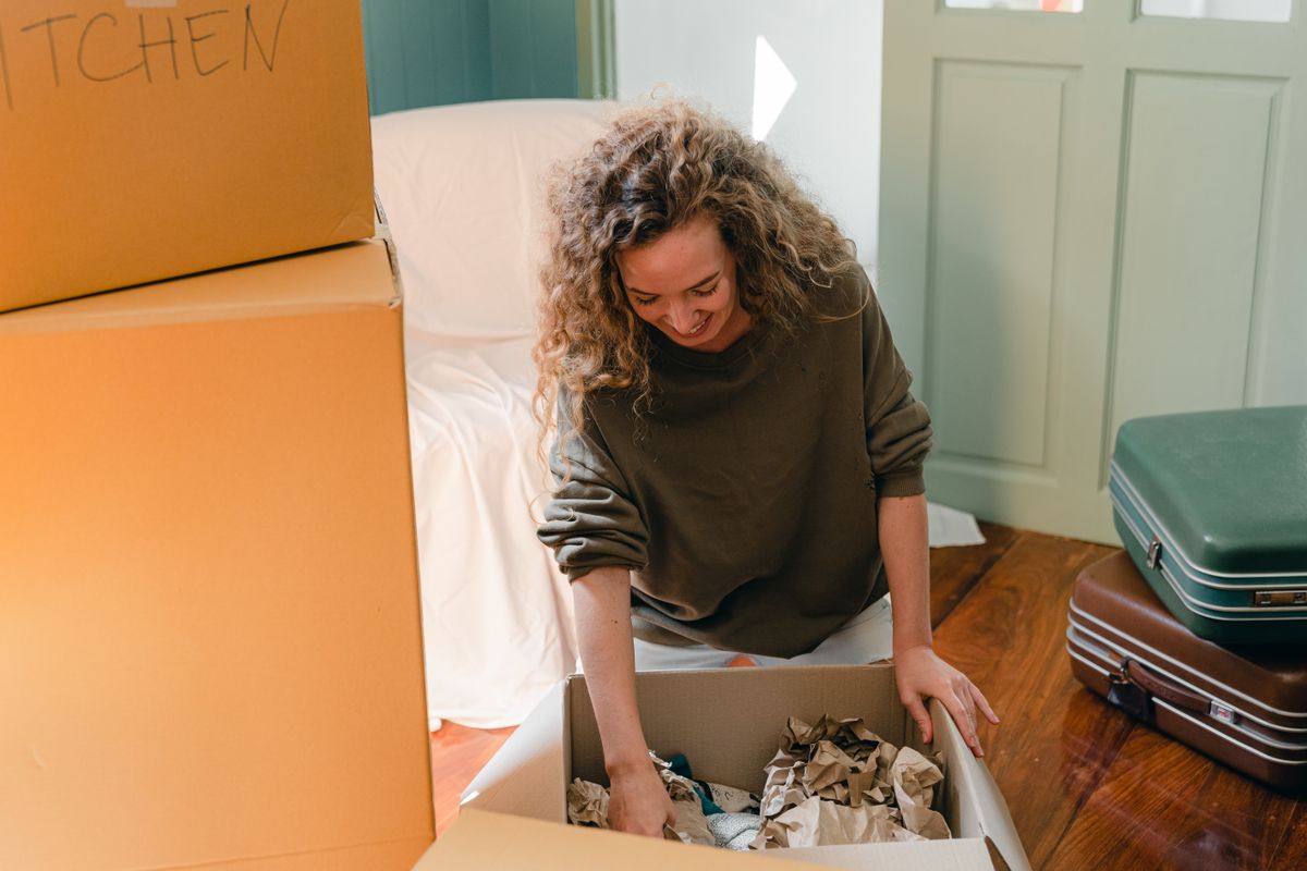 A smiling woman unpacks a delivery box at home