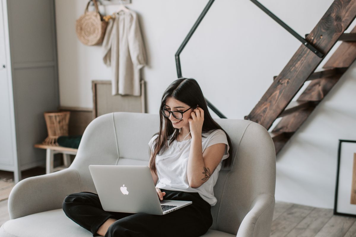 A woman smiles while shopping on her laptop from her couch