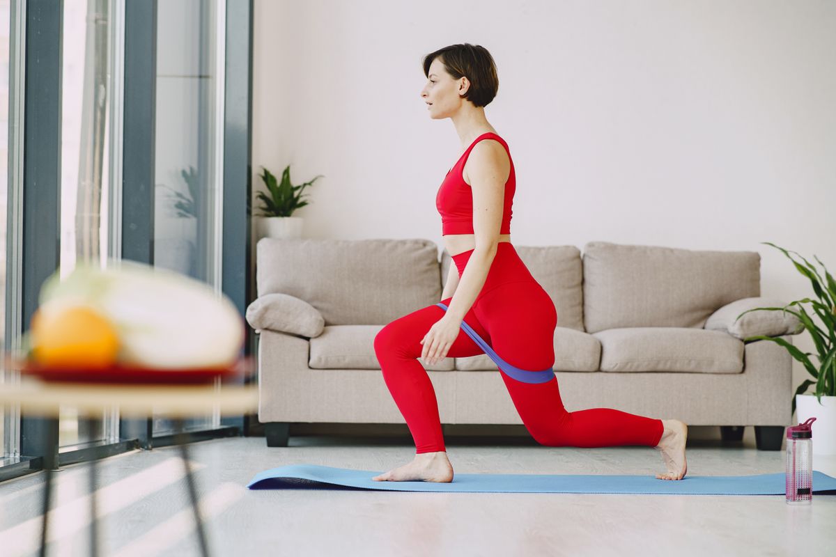 A woman does lunges on a yoga mat in her living room