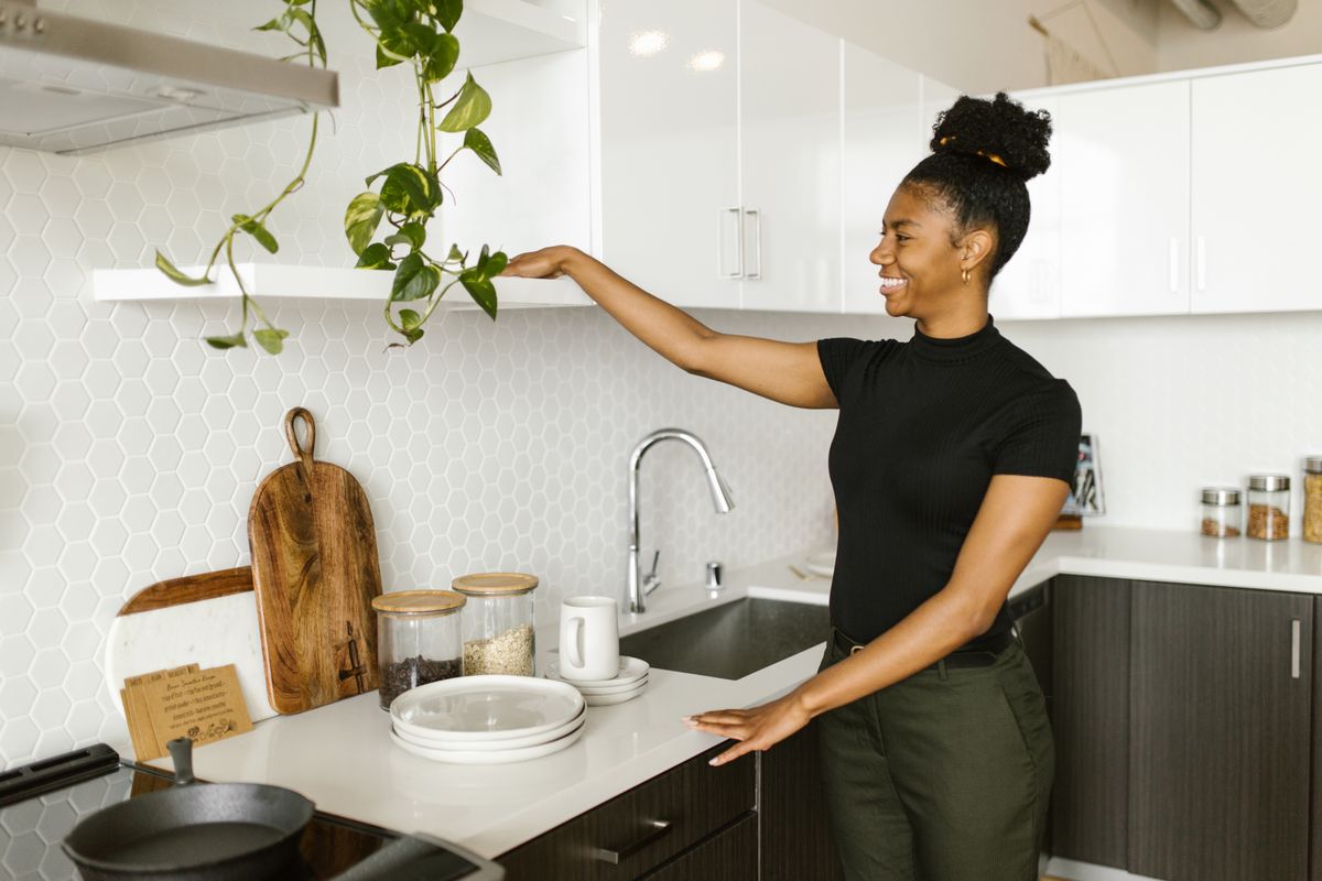 A smiling woman organizes her kitchen shelves