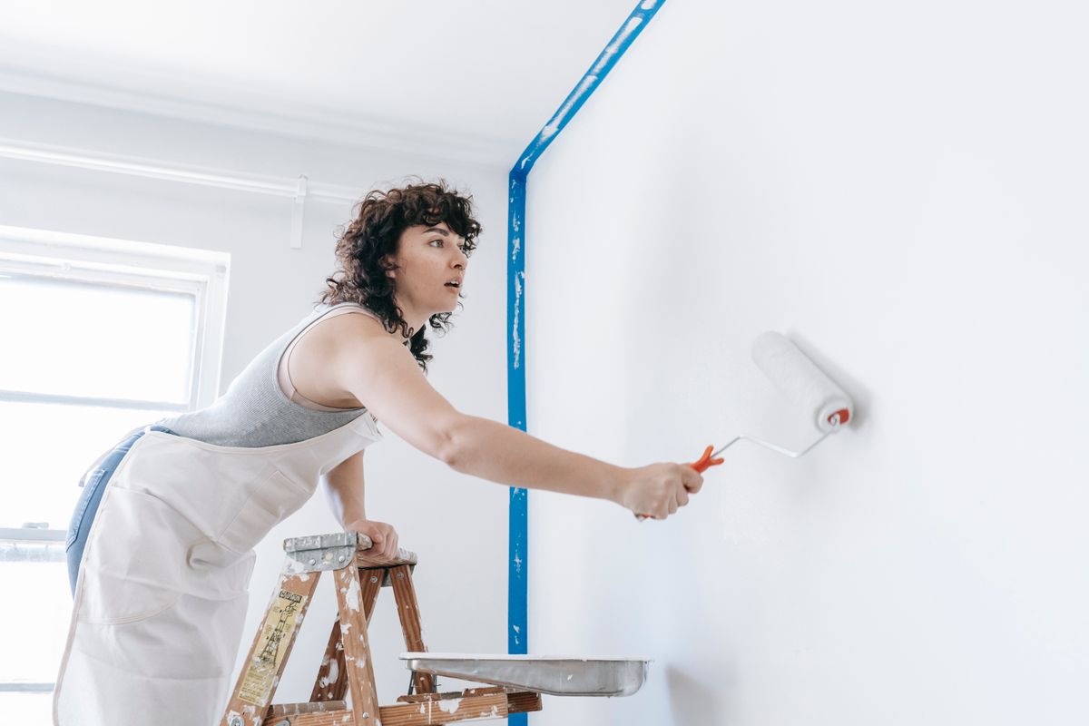 A woman paints a wall with a roller during a home project