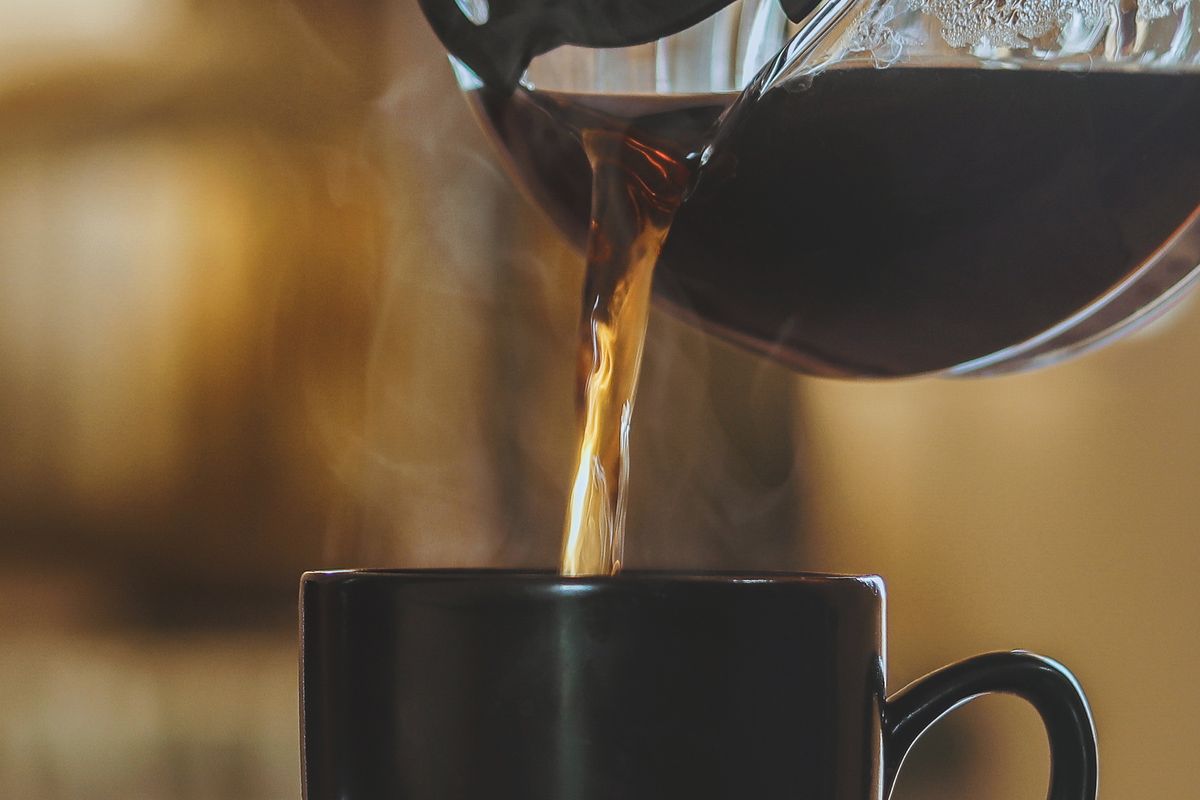 Fresh coffee pouring from the carafe into a mug