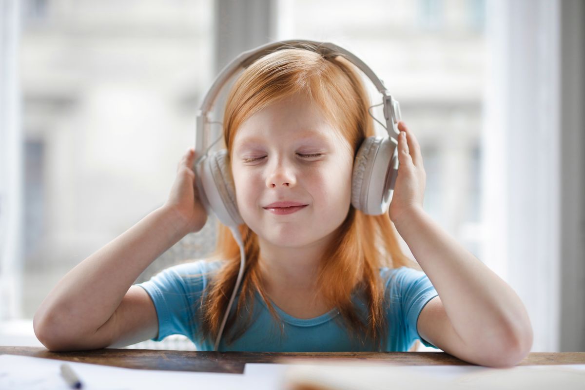 A girl smiling with her eyes closed wearing headphones