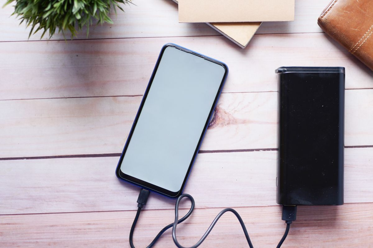A phone charging from a power bank on a desk