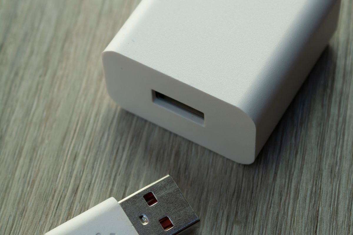 A white USB wall charger and cable on a wooden table